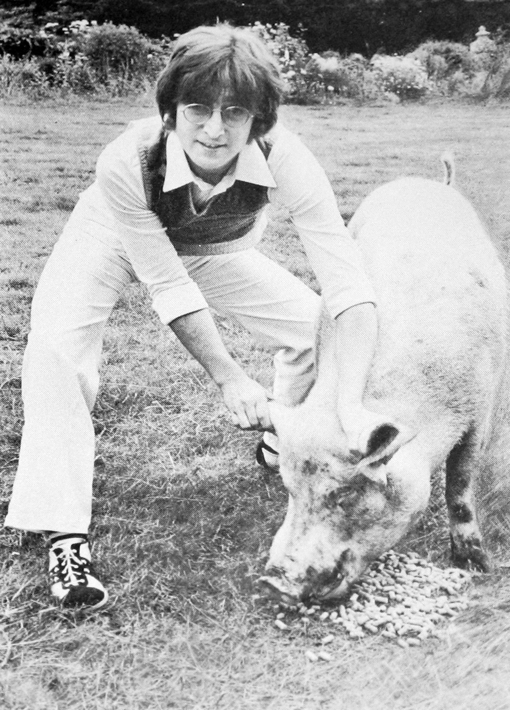 Photo of John Lennon holding a pig by it's ears